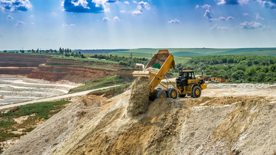 Blick auf eine Bergbaulandschaft mit einer Abraumhalde und einem Kipplaster im Vordergrund